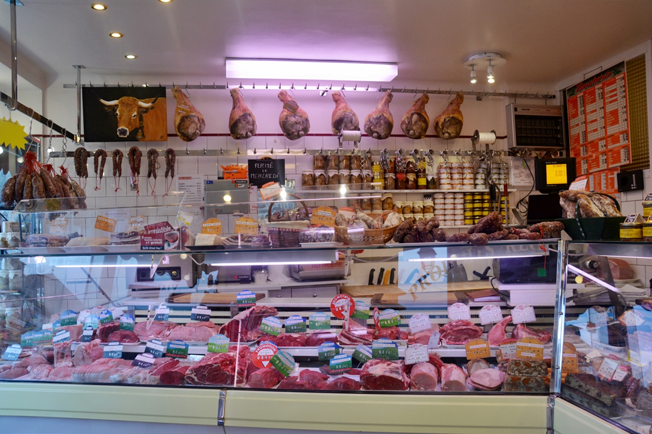 Le comptoir de la boucherie sous les jambons affinés et la tête d'Aubrac empaillée